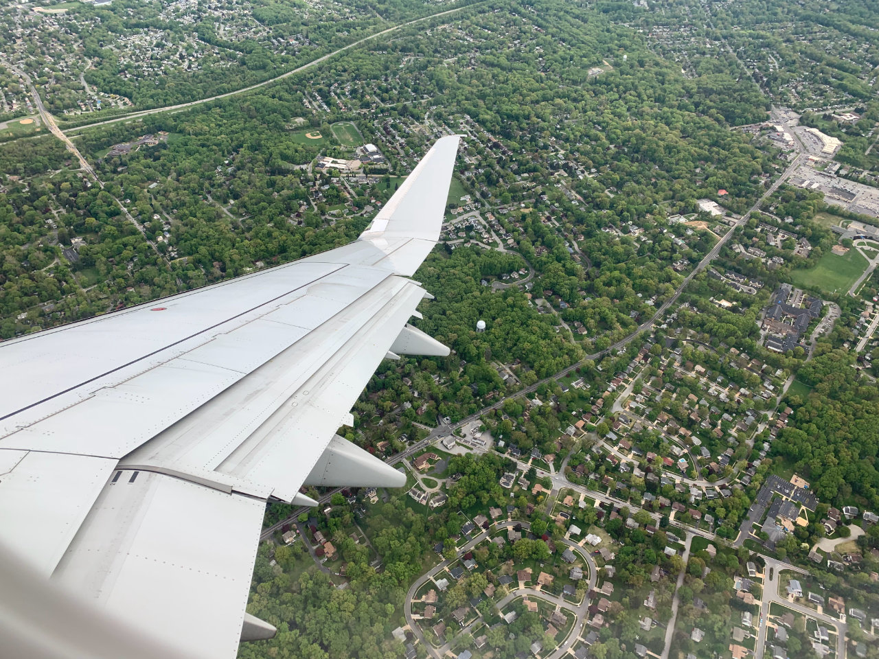 View from a banking plane of green trees and neatly arranged houses